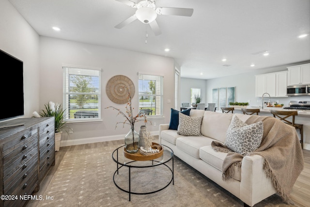 living room with ceiling fan, light hardwood / wood-style flooring, and sink