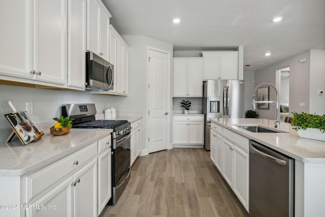 kitchen featuring stainless steel appliances, light hardwood / wood-style floors, sink, and white cabinets