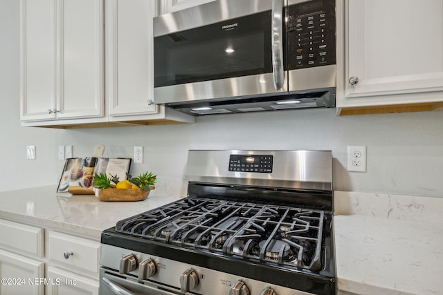 kitchen featuring stainless steel appliances, white cabinetry, and light stone countertops