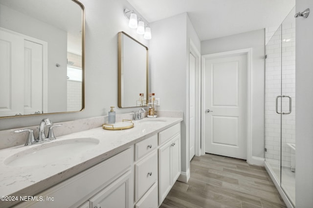 bathroom featuring double sink vanity, walk in shower, and hardwood / wood-style floors