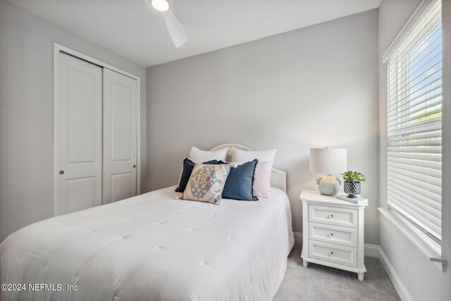 bedroom with ceiling fan, light carpet, and a closet