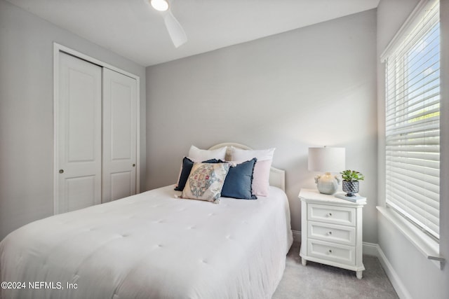 bedroom featuring light colored carpet, a closet, and ceiling fan