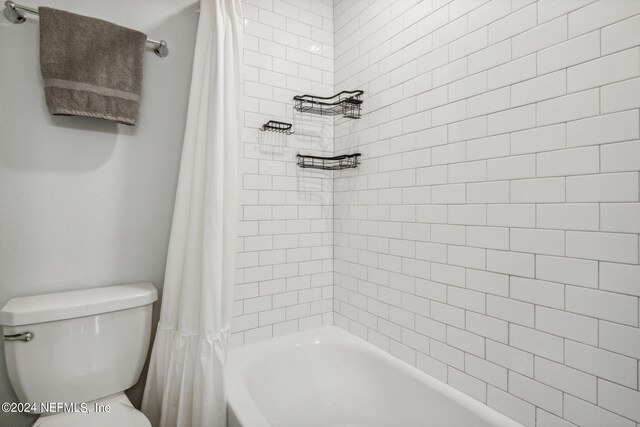 bathroom featuring shower / tub combo and toilet