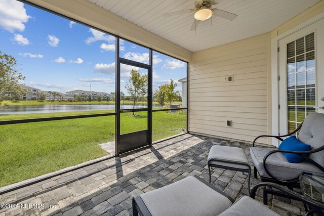 unfurnished sunroom with ceiling fan and a water view