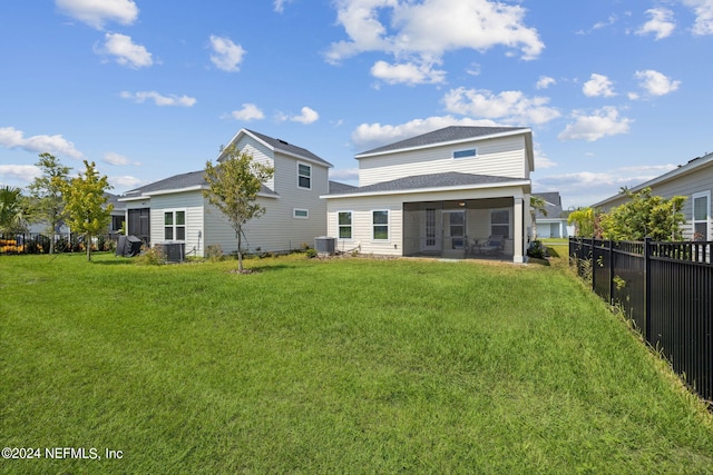 rear view of property featuring a sunroom, a yard, and central AC