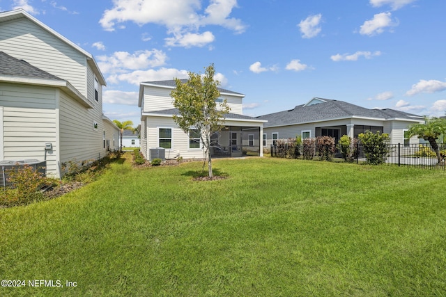 back of house featuring central AC, a sunroom, and a lawn