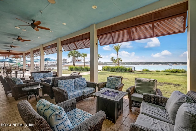 view of patio with ceiling fan, a water view, and an outdoor living space with a fire pit