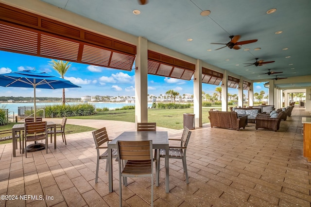 view of patio featuring ceiling fan, a water view, and an outdoor living space