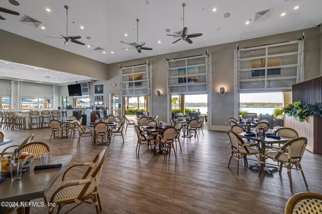 dining area featuring a towering ceiling, hardwood / wood-style floors, and ceiling fan