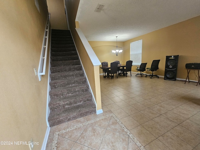 staircase with light tile patterned flooring, a textured ceiling, and a notable chandelier