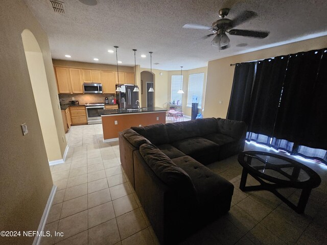 tiled living room with sink, a textured ceiling, and ceiling fan