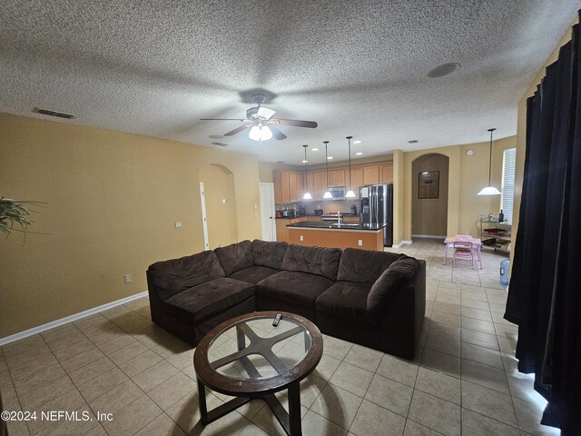 tiled living room with a textured ceiling and ceiling fan