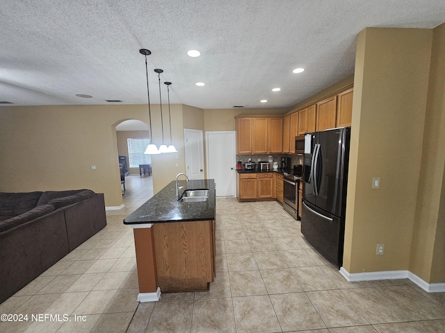 2727 Wood Stork Trl, Orange Park, FL 32073 - kitchen with a sink, open floor plan, stainless steel appliances, arched walkways, and dark stone counters