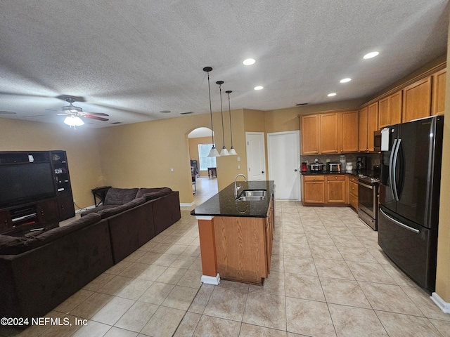 kitchen featuring stainless steel electric range, light tile patterned floors, an island with sink, ceiling fan, and black fridge