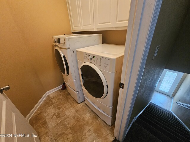 washroom with washing machine and dryer, cabinets, and light tile patterned floors