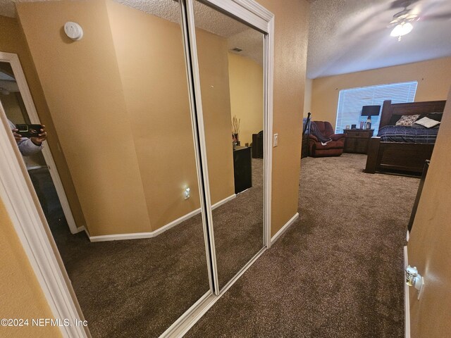 hallway with a textured ceiling and carpet flooring