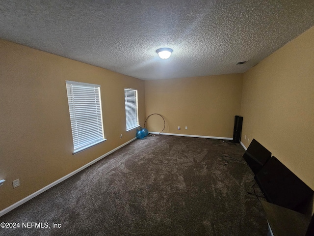 carpeted empty room featuring a textured ceiling