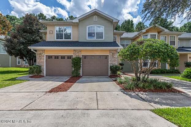 view of front of home with a garage, stone siding, and driveway