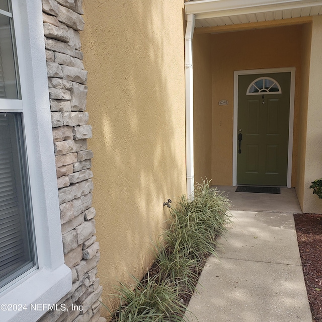 entrance to property featuring stone siding and stucco siding