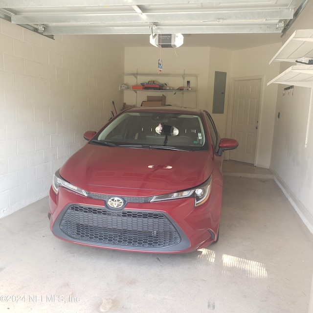 garage featuring a garage door opener, concrete block wall, and electric panel