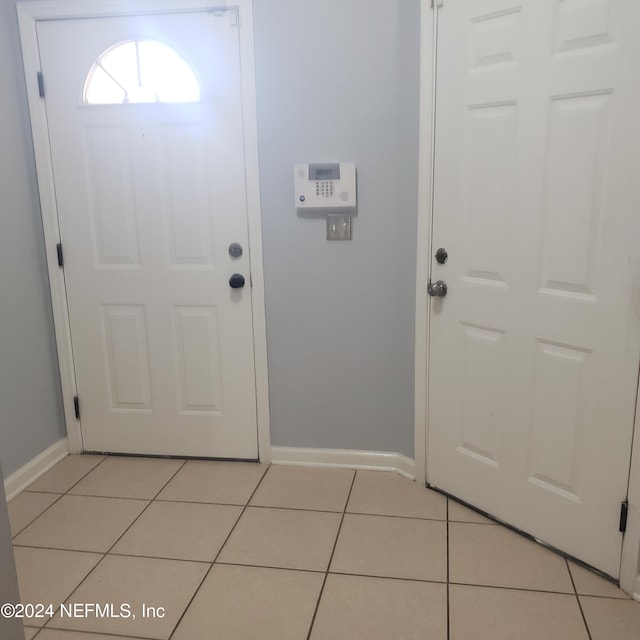 foyer entrance featuring light tile patterned flooring and baseboards