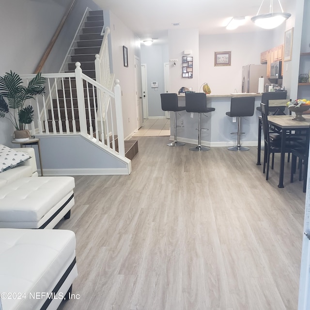 living area featuring baseboards, light wood finished floors, and stairs