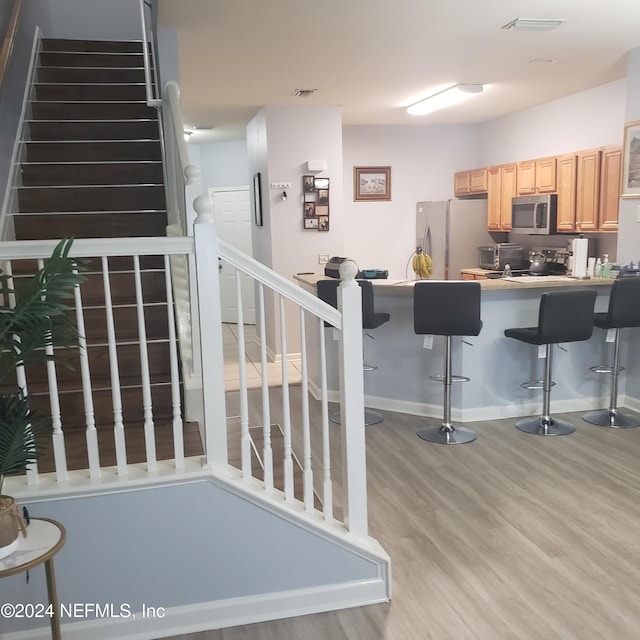 kitchen with visible vents, a kitchen bar, appliances with stainless steel finishes, and wood finished floors