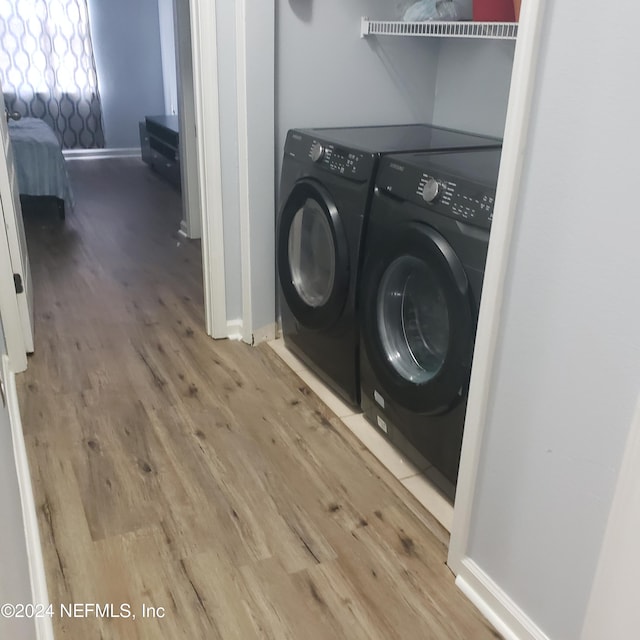 washroom featuring laundry area, separate washer and dryer, wood finished floors, and baseboards