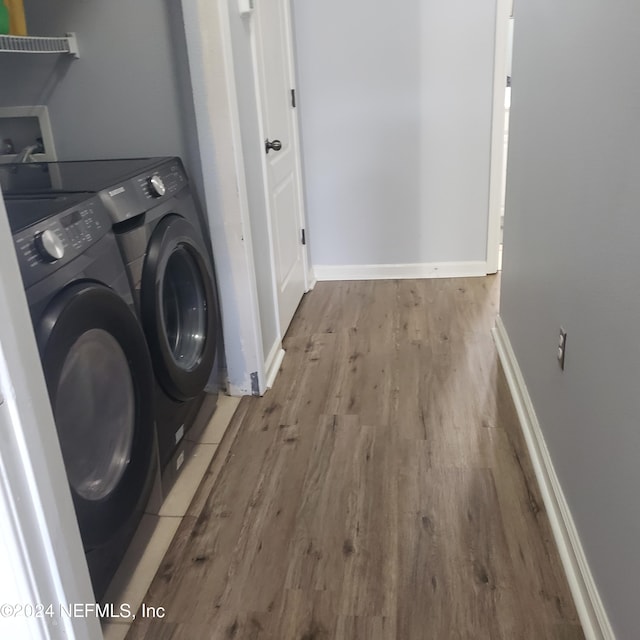 laundry area with laundry area, washer and clothes dryer, light wood-style flooring, and baseboards