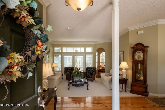 living room featuring crown molding, a textured ceiling, and light wood-type flooring