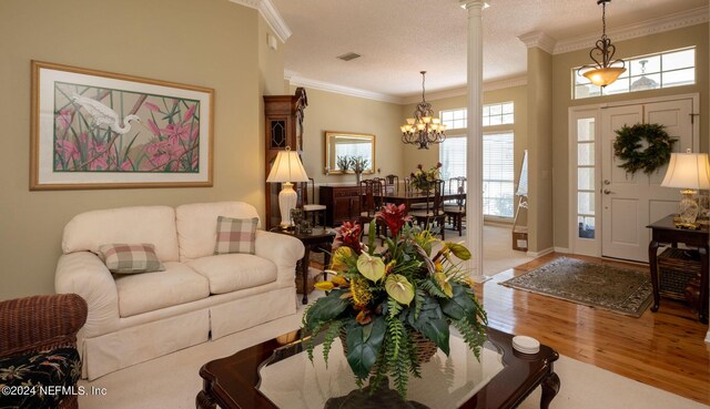 living room with a textured ceiling, an inviting chandelier, crown molding, and hardwood / wood-style flooring