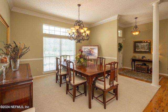 dining area with hardwood / wood-style floors, crown molding, a textured ceiling, and ornate columns