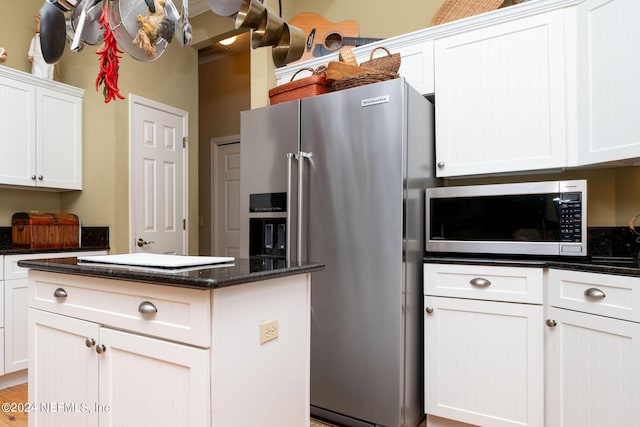 kitchen with white cabinetry, appliances with stainless steel finishes, and dark stone countertops