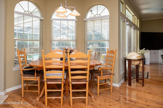 dining space featuring crown molding, a chandelier, and light hardwood / wood-style flooring