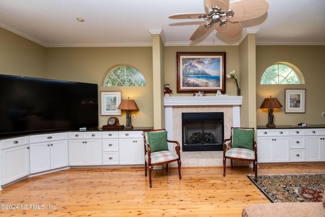 living room featuring light hardwood / wood-style flooring, a tile fireplace, and crown molding