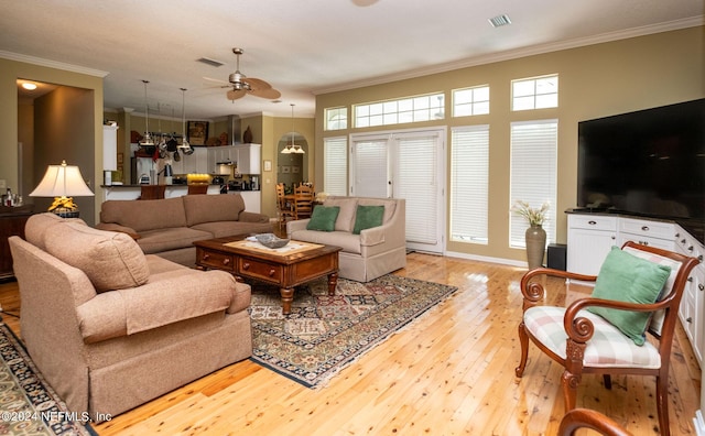 living room with ceiling fan, light wood-type flooring, and ornamental molding