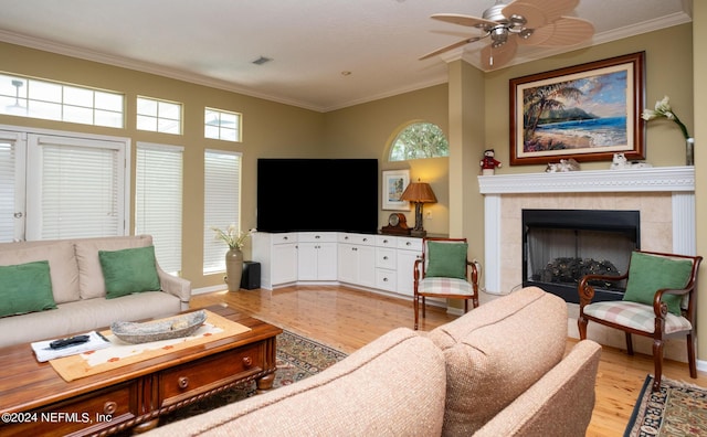 living room with ceiling fan, ornamental molding, light hardwood / wood-style floors, and a tile fireplace