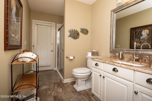 bathroom featuring vanity, a textured ceiling, a shower with door, and toilet