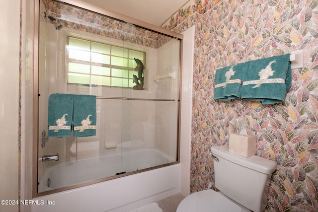 bathroom featuring combined bath / shower with glass door, a textured ceiling, and toilet