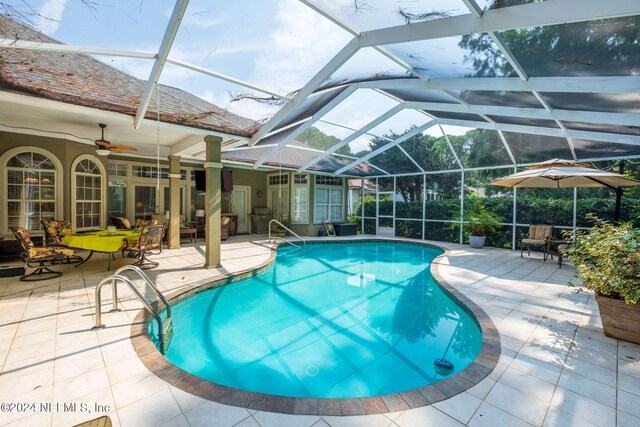 view of pool with ceiling fan, glass enclosure, and a patio area