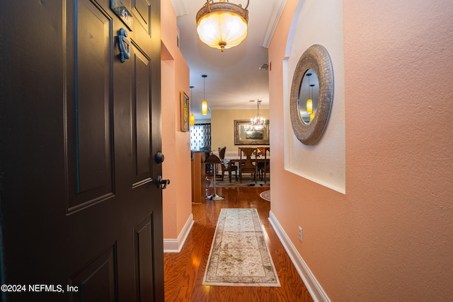 hall featuring an inviting chandelier, dark hardwood / wood-style floors, and ornamental molding