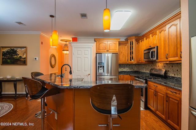 kitchen with appliances with stainless steel finishes, glass insert cabinets, a breakfast bar, and visible vents