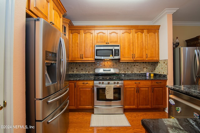 kitchen featuring appliances with stainless steel finishes, dark stone counters, tasteful backsplash, and wood-type flooring