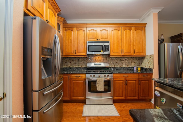 kitchen with appliances with stainless steel finishes, decorative backsplash, wood finished floors, and ornamental molding