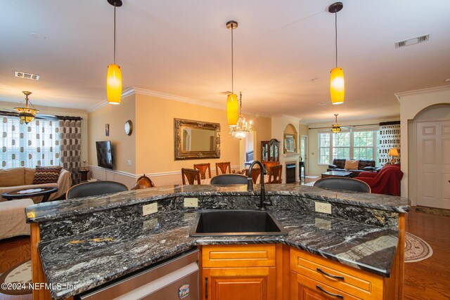 kitchen featuring hanging light fixtures, sink, dark stone countertops, and dishwasher