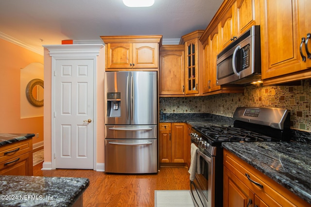 kitchen featuring brown cabinetry, ornamental molding, stainless steel appliances, and light wood finished floors