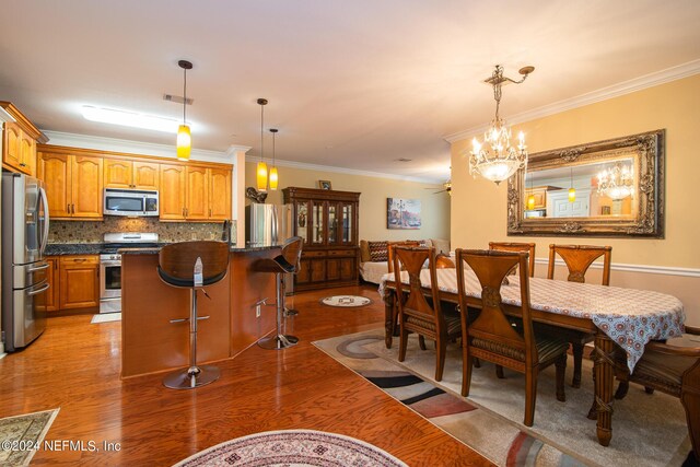 dining room with an inviting chandelier, crown molding, and light wood-type flooring