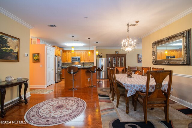 dining area featuring crown molding, a chandelier, and wood-type flooring