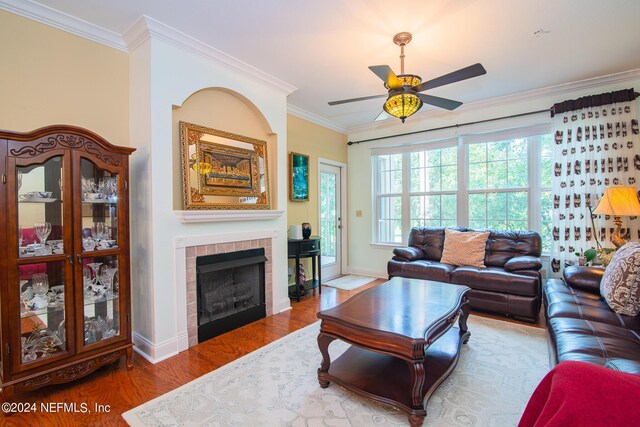 living room with a fireplace, crown molding, hardwood / wood-style floors, and ceiling fan