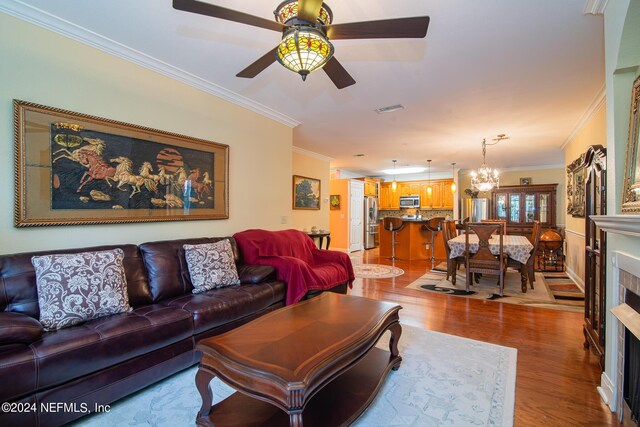 living room featuring ornamental molding, wood-type flooring, and ceiling fan with notable chandelier